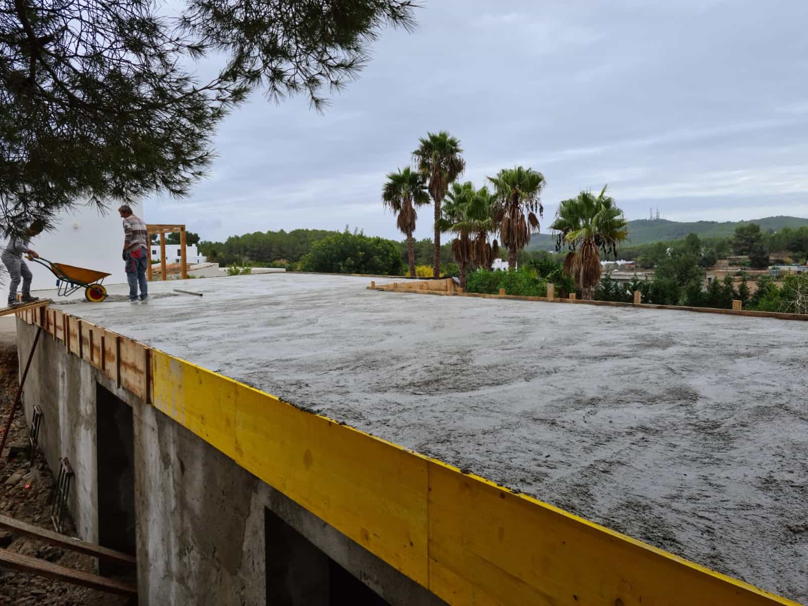Construcción de forjado de hormigón con encofrado de madera y operarios trabajando en Ibiza