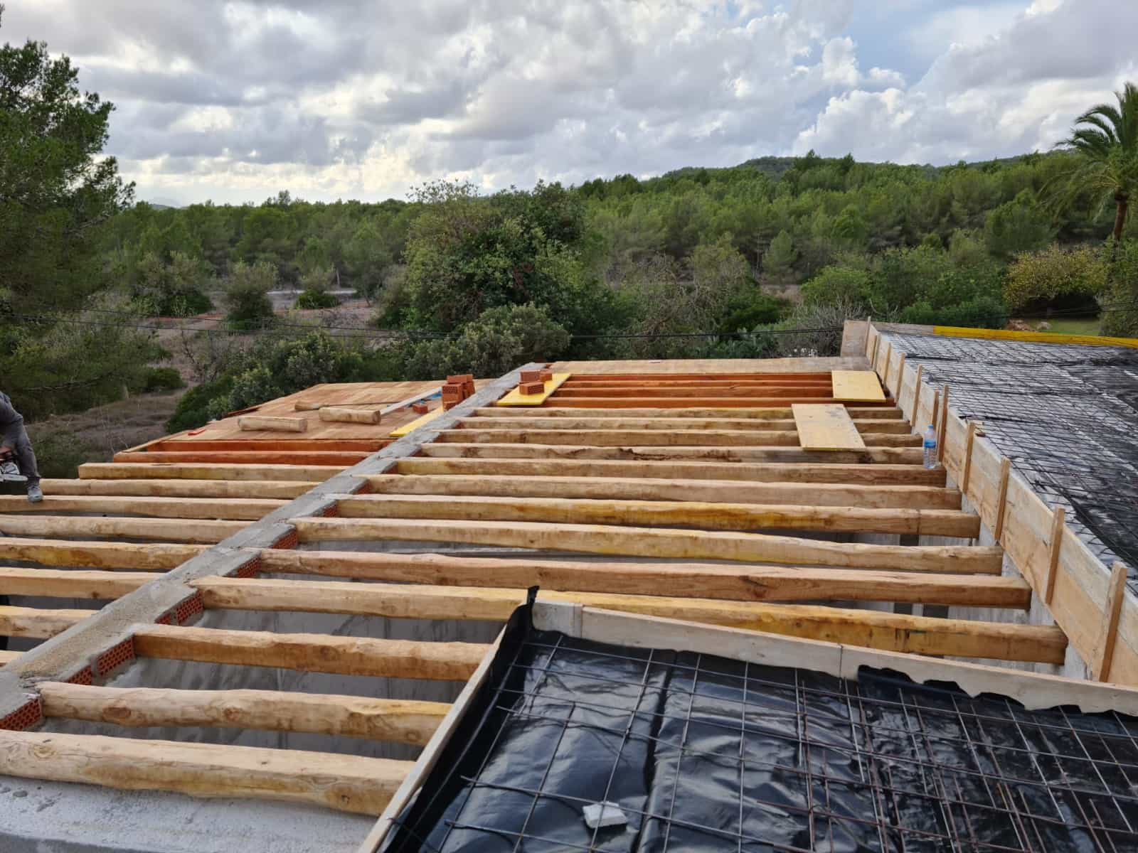 Construcción de forjado con vigas de madera natural y mallazo de acero en una vivienda de Ibiza