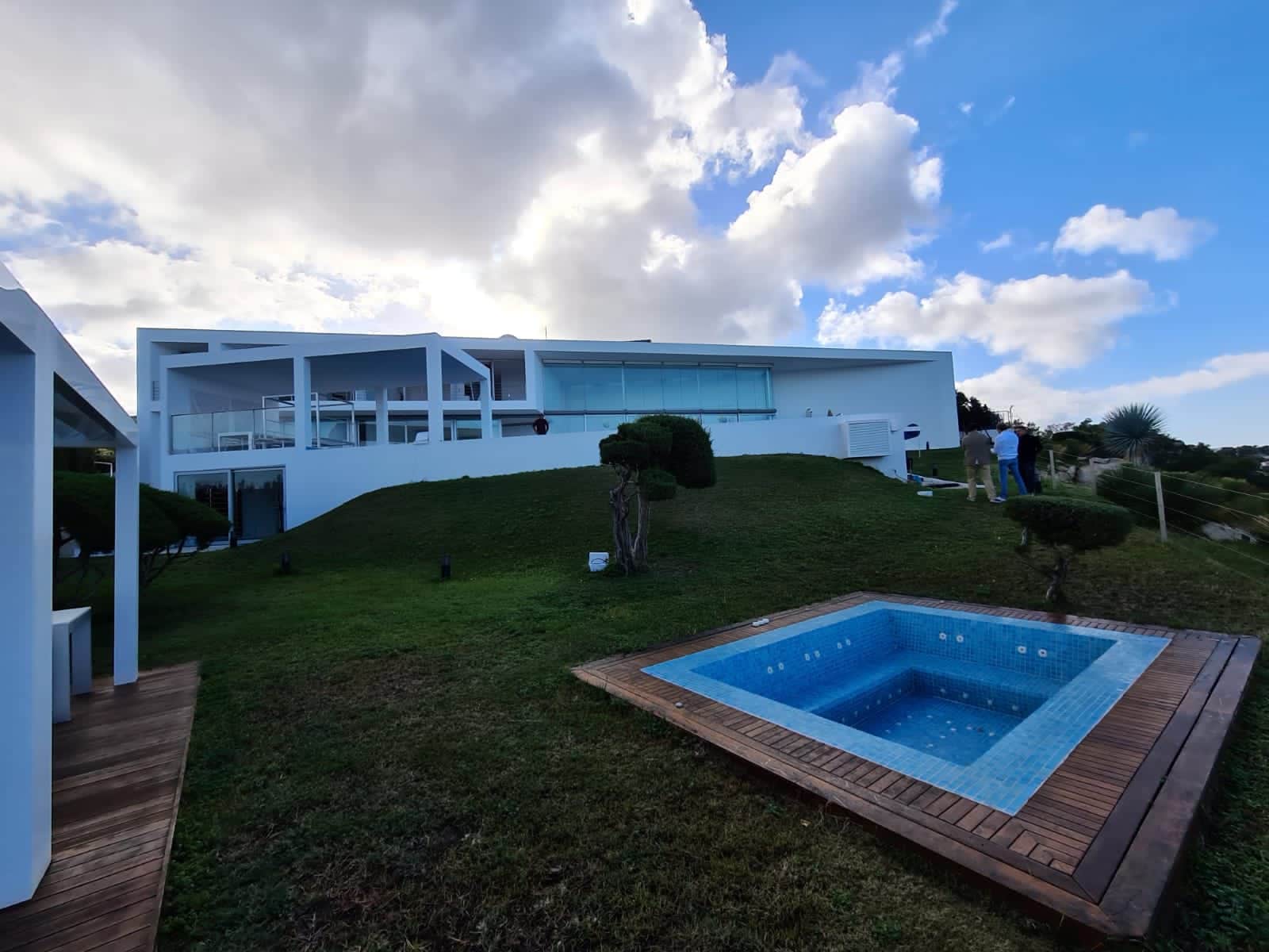 Construcción de piscina con gresite azul y tarima de madera junto a fachada blanca en Ibiza