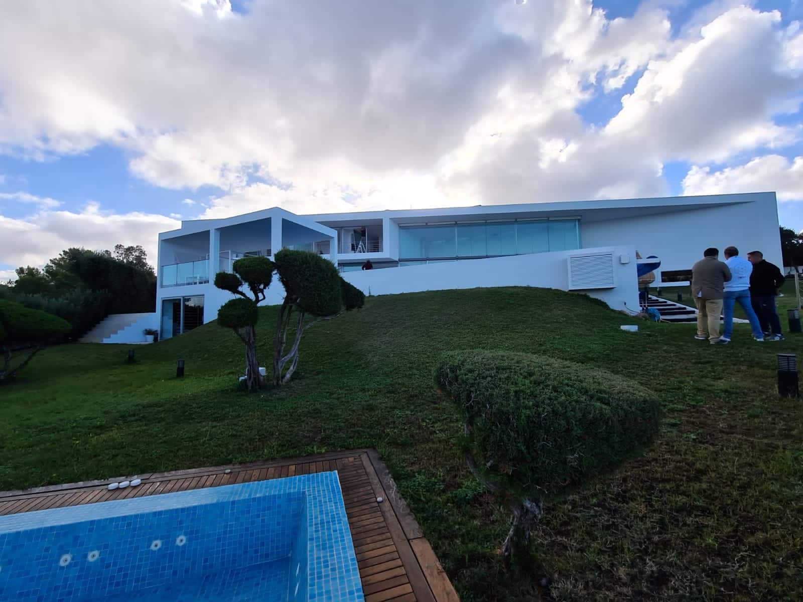 Rehabilitación de fachada minimalista blanca con grandes ventanales y piscina en primer plano en Ibiza