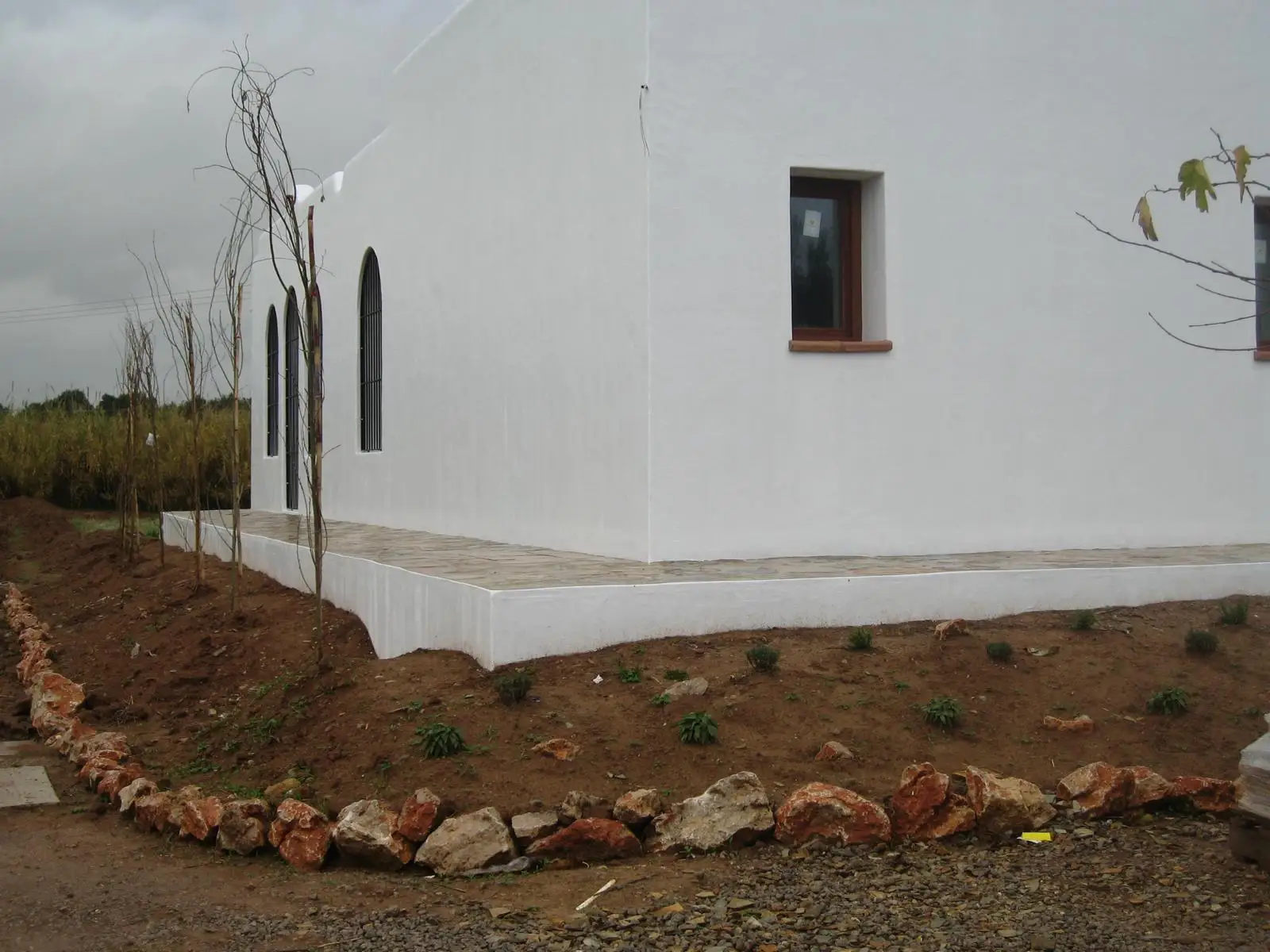 Rehabilitación de fachada blanca con detalles en piedra natural y carpintería de madera en Ibiza